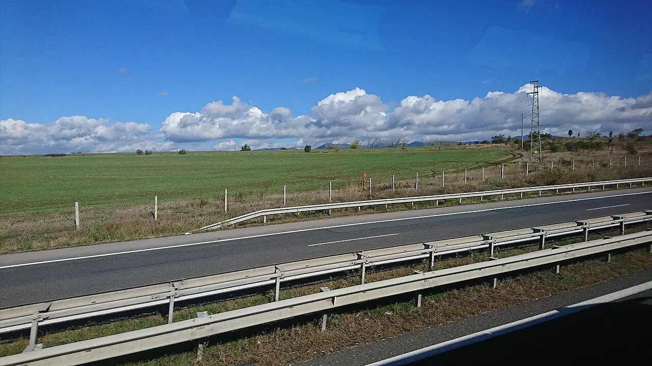 Hemus motorway running beside green fields under a cloudy sky.